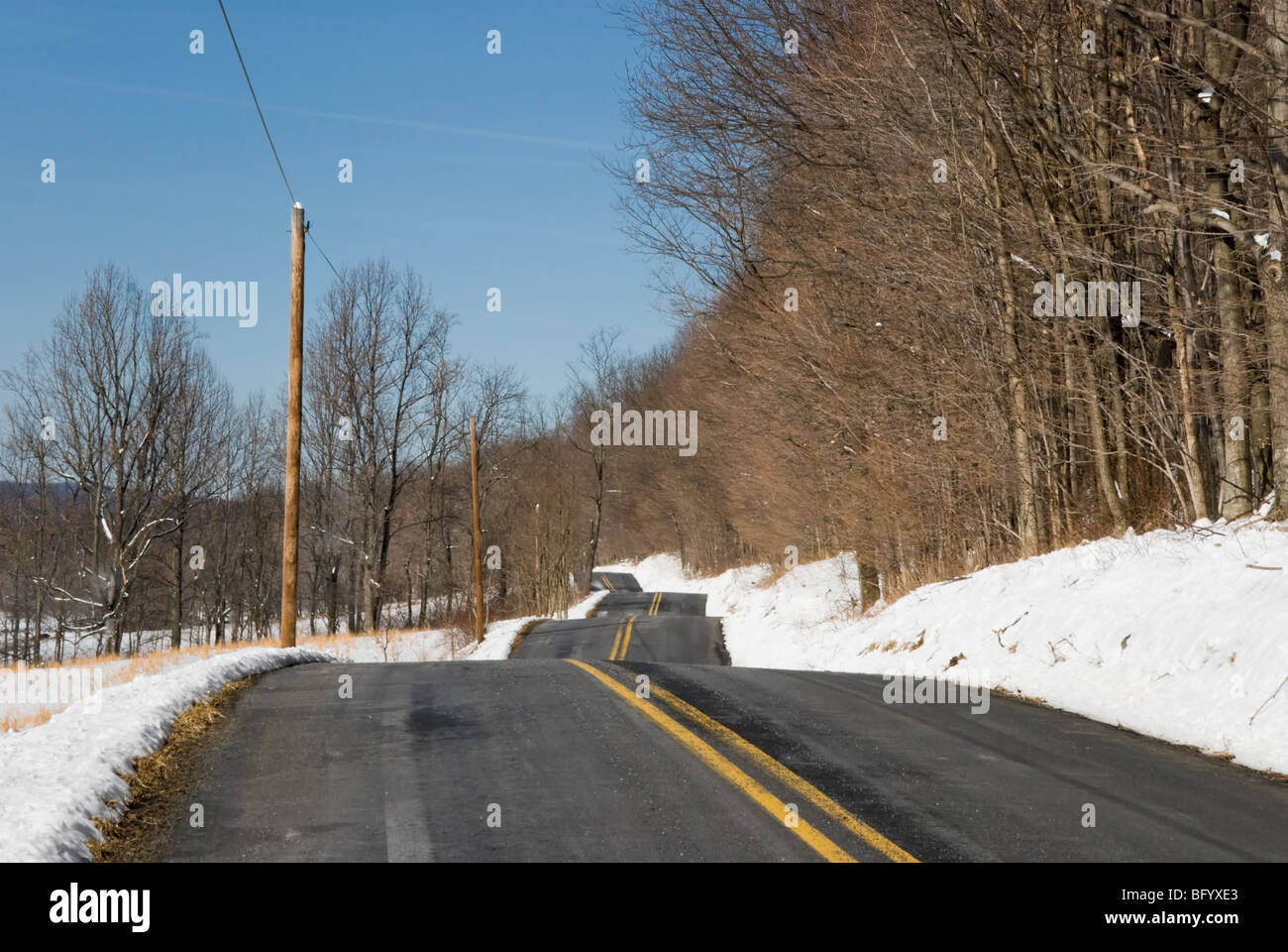 Rolling hills on a bumpy two lane black top road in rural Pennsylvania countryside, USA. Stock Photo
