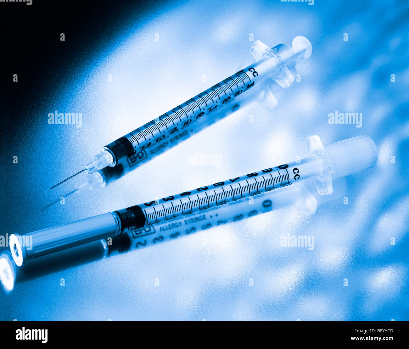 Two medical syringes beautifully displayed on a dabbled background with a blue monochromatic look Stock Photo