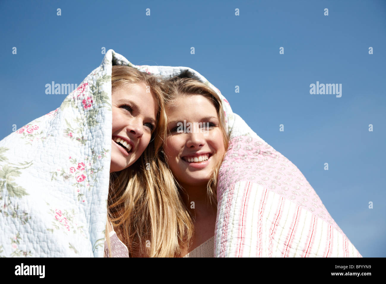 Two girls wrapped up in blanket outdoors Stock Photo Alamy