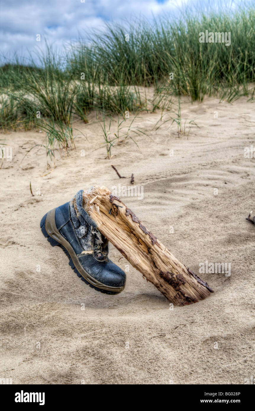 Walking boot thats been washed up on a beach and placed on driftwood at Pembrey, Wales Stock Photo
