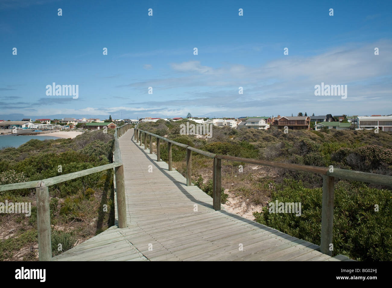 The boardwalk in Struisbaai follows the shore along Skoonberg Bay to the harbor in the fishing village of Struisbaai, SA. Stock Photo