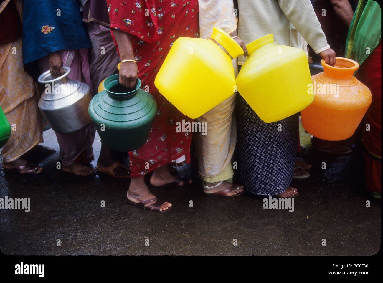 Men and women stand in line with jugs to get water from a water truck in Ooty, India Stock Photo