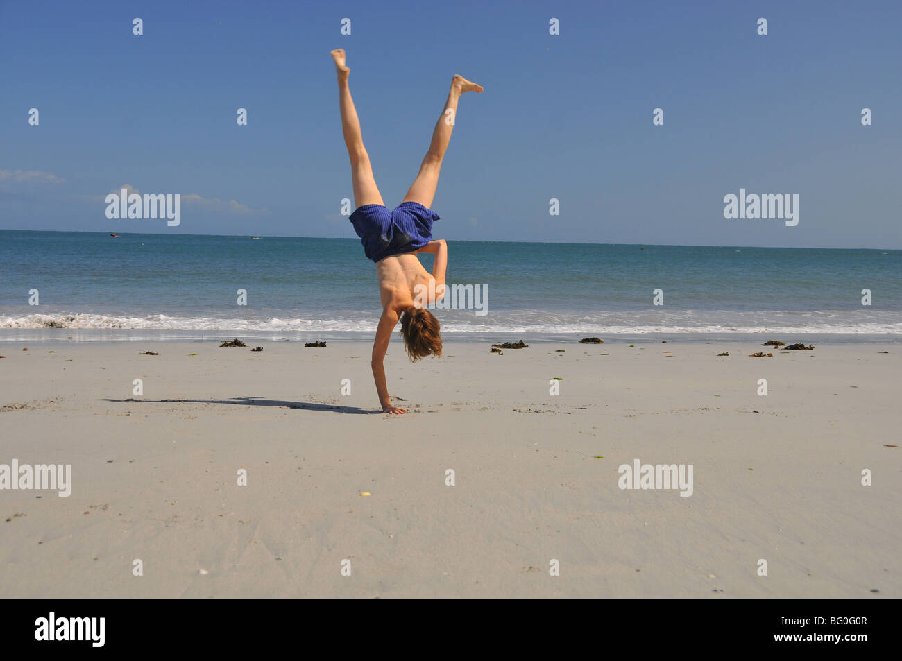 young white woman jumping on the sand with bare breasted legs in air one  hands on Stock Photo - Alamy