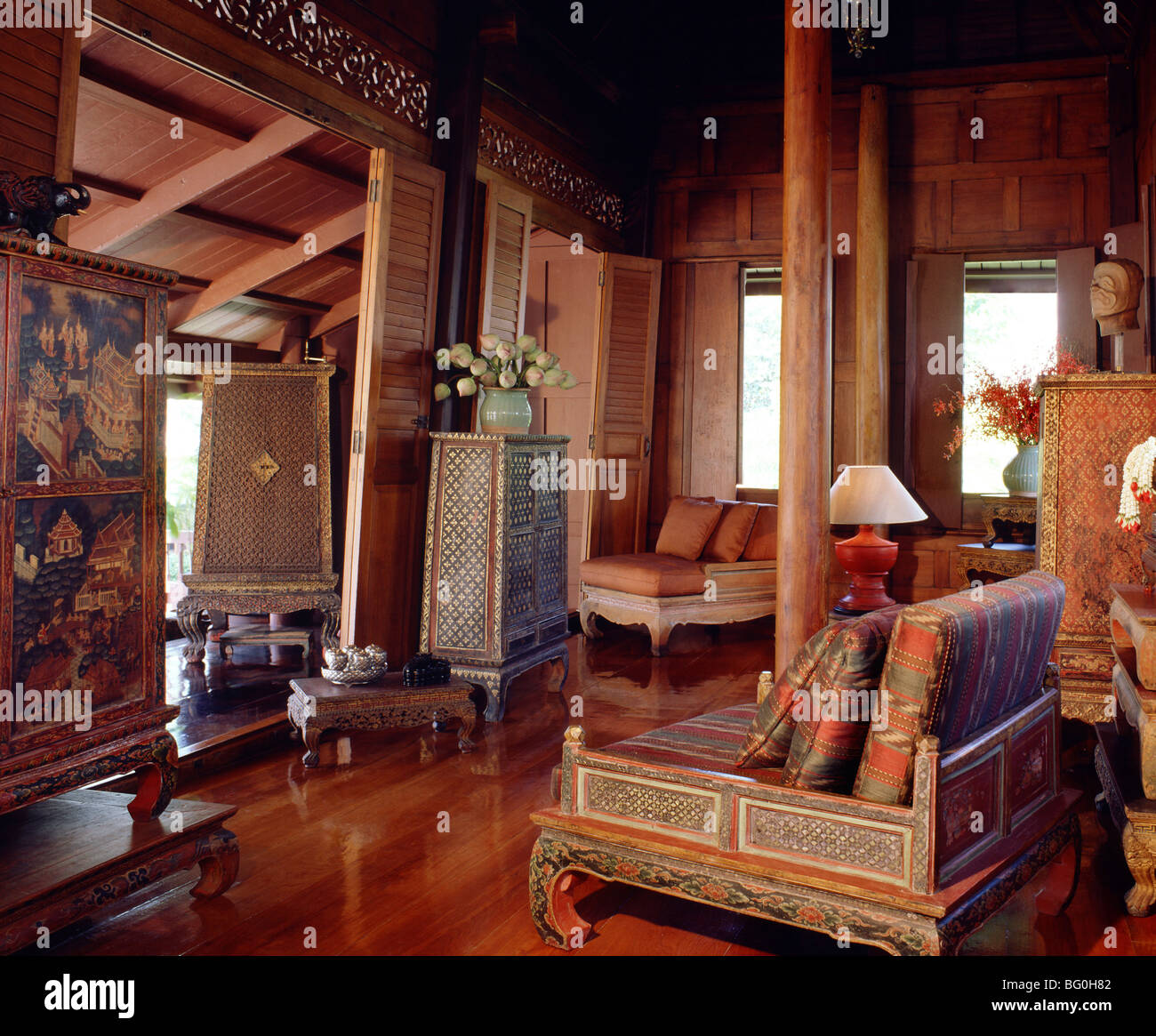 Traditional Thai house with old manuscript cabinet, table, and silk cushions in teak living room in Thailand, Asia Stock Photo