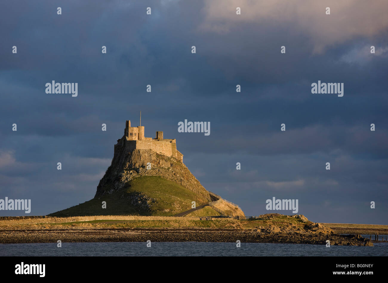 Lindisfarne Castle bathed in afternoon sunlight against a stormy sky, Holy Island. Northumberland, England, United Kingdom Stock Photo