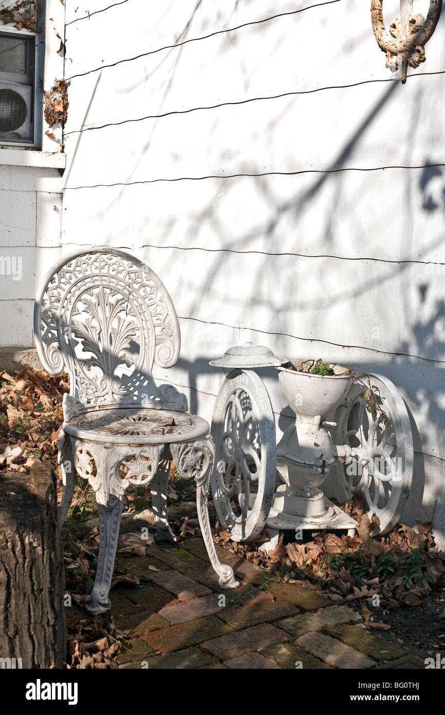 sunny corner of country garden in December with old cast iron garden furniture & fallen autumn leaves, Montgomery New York Stock Photo