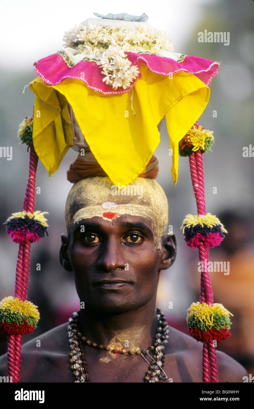 A pilgrim/devotee brings an offering to the Palani Murugan Temple and is taking part in the Thaipusam festival to honor Lord Subramaniam (also known as Lord Muruga), son of Shiva. The offering balanced on his head is a form of kavadi and symbolizes the burden he bears to show his devotion. Thousands of Hindus like this man come to seek penance and absolution for past sins and show gratitude to God for blessings during the year Stock Photo