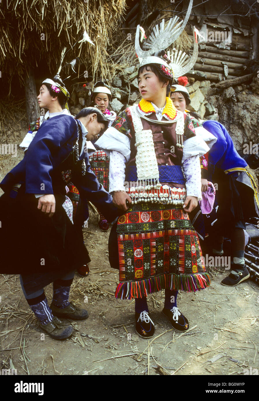 A mother gets her daughter ready to participate in a festival. These people are members of the Miao ethnic minority living in Guizhou Province in China. Women's headdresses take special importance in Miao culture. When a girl is born, her parents will start saving money to make fancy silver head ornaments that can weigh several kilograms. Stock Photo