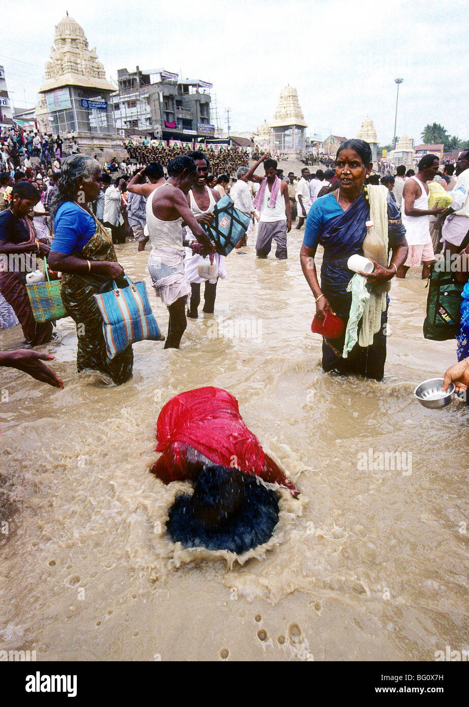 Pilgrims and devotees take a holy dip and splash water on one another in the Mahamaham temple tank during the Hindu Kumb Mela festival that is celebrated every 12 years in a small temple-town called Kumbakonam in the state of Tamil Nadu, India. It is believed that taking a bath or sprinkling water of the tank on their bodies will cleanse them of all their sins. This festival, called the Mahamaham festival, took place in March of 2004. Stock Photo