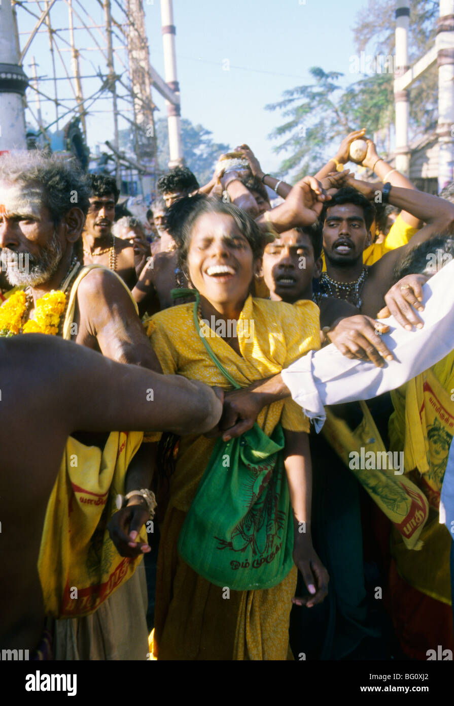 A group of yellow robed devotees and pilgrims have come from a distant village and are dancing and singing their way through the streets of Palani in the south India state of Tamil Nadu during the annual Hindu Thaipusam festival. They are celebrating the youngest son of Shiva, Lord Murugan's birthday and will ultimately ascend the steps to his temple in Palani. Stock Photo
