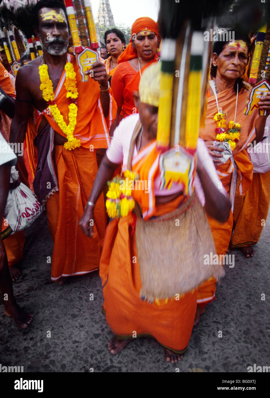 A group of orange robed devotees and pilgrims have come from a distant village and are dancing and singing their way through the streets of Palani in the south India state of Tamil Nadu during the annual Hindu Thaipusam festival. They are celebrating the youngest son of Shiva, Lord Murugan's birthday and will ultimately ascend the steps to his temple in Palani Stock Photo