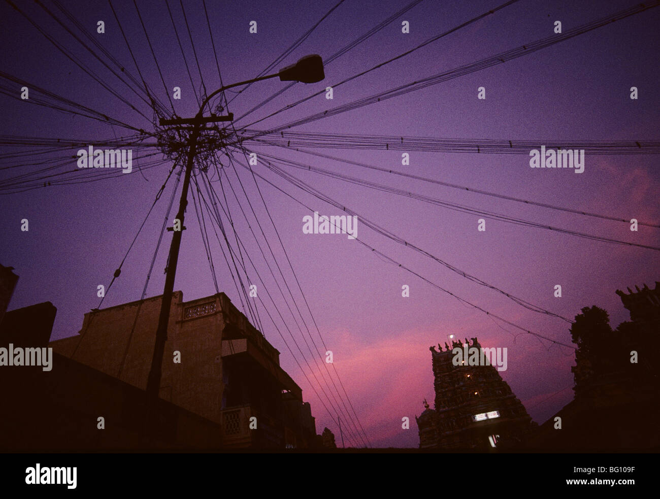 A jumble of power, telephone lines and street light at sunrise in