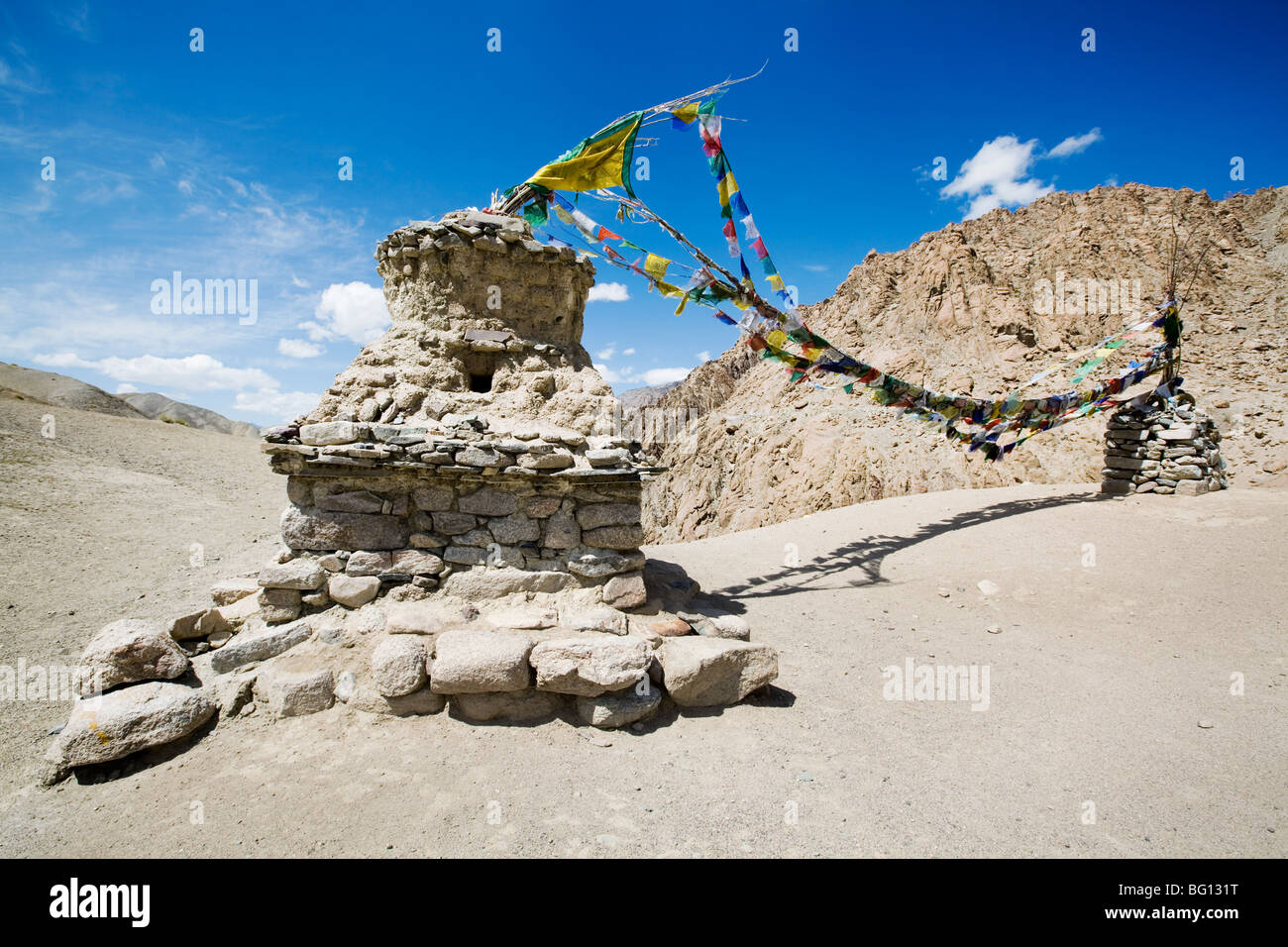 Stupas and Buddhist prayer flag mark the high pass on a mountain trekking route in Ladakh, Indian Himalayas. Stock Photo