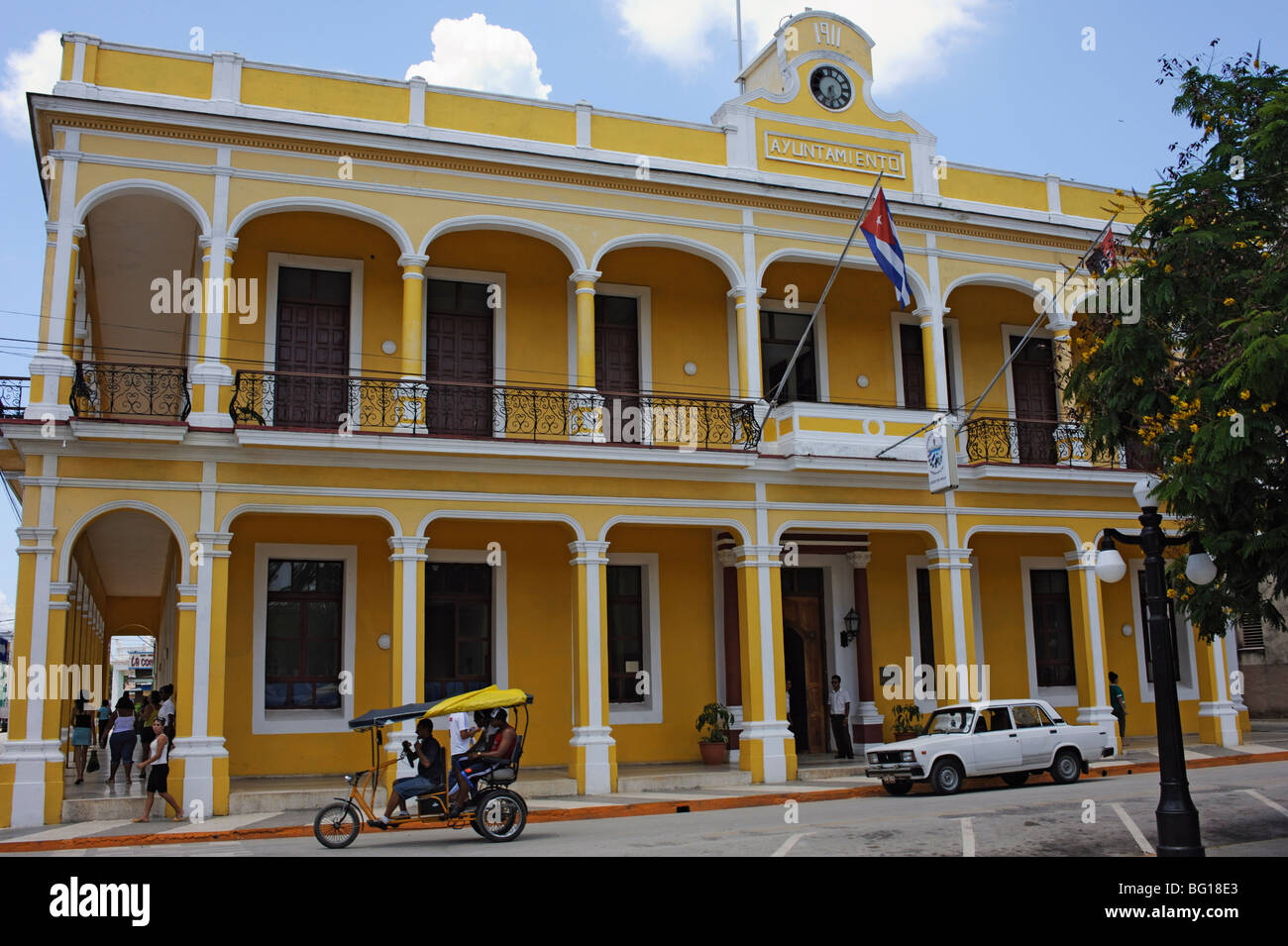 A bici-taxi (bicycle rickshaw) and Russian Lada car in front of Council House, Marti Square, Ciego de Cvila, Cuba, West Indies Stock Photo