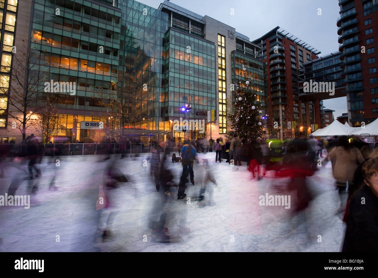 UK, England, Manchester, Spinningfields, parents and children on Christmas ice skating rink at night Stock Photo