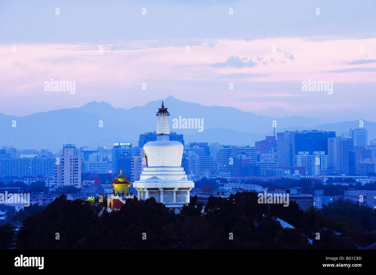 An illuminated White Pagoda and city buildings at sunset, Beihai park, Beijing, China, Asia Stock Photo