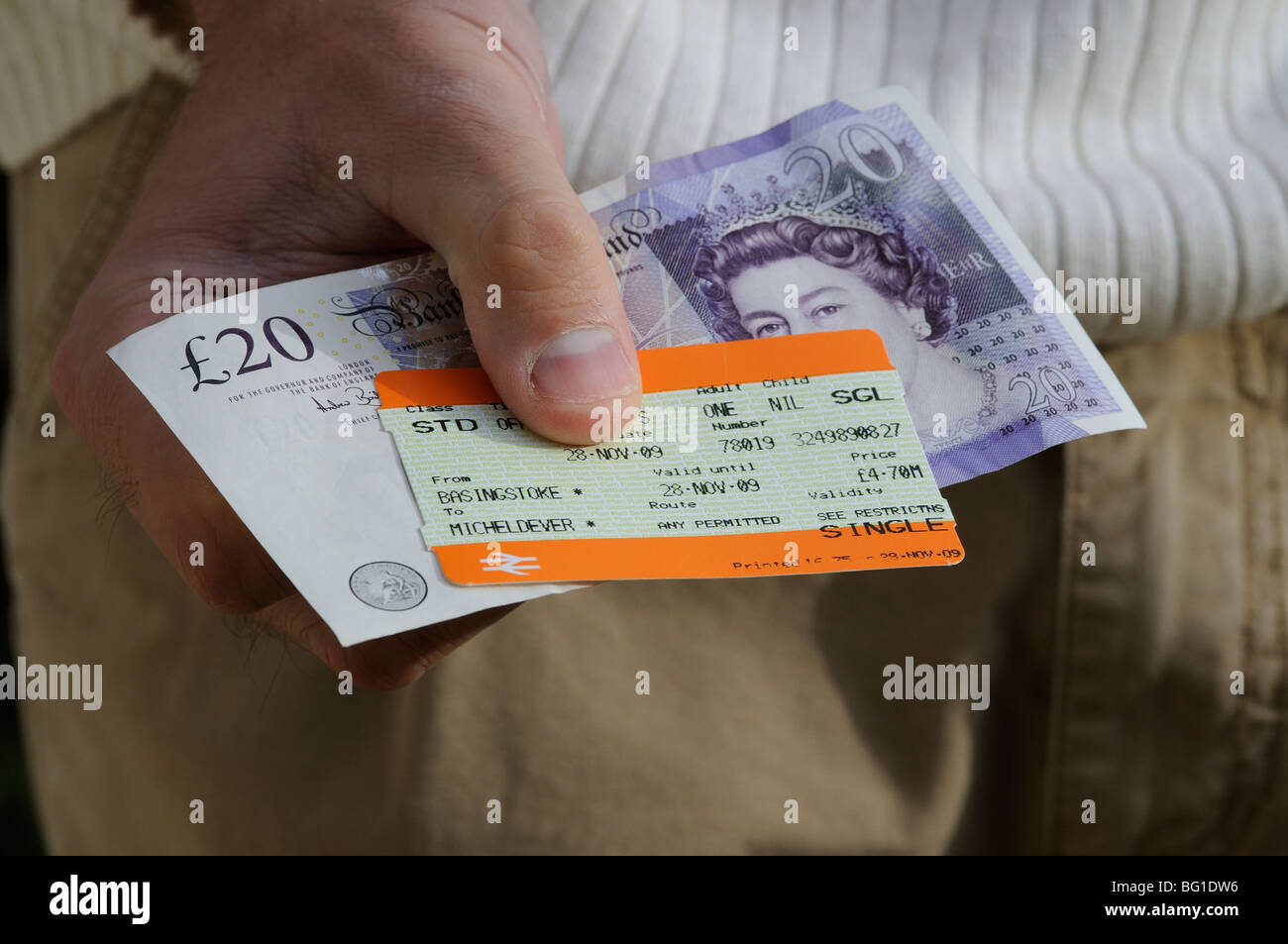 railway ticket and twenty pound note being held in a mans hand Stock Photo