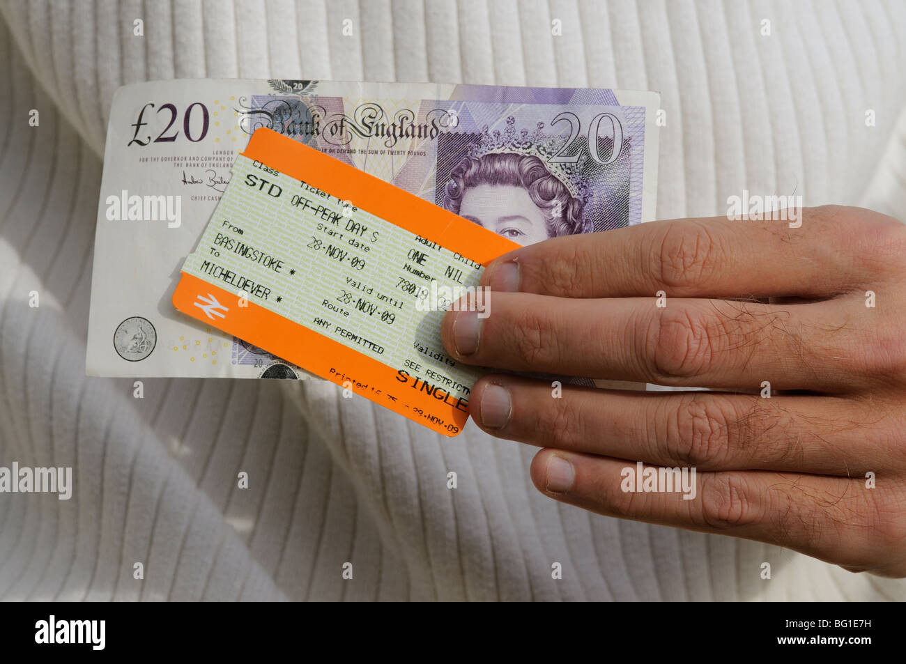 railway ticket and twenty pound note being held in a mans hand Stock Photo