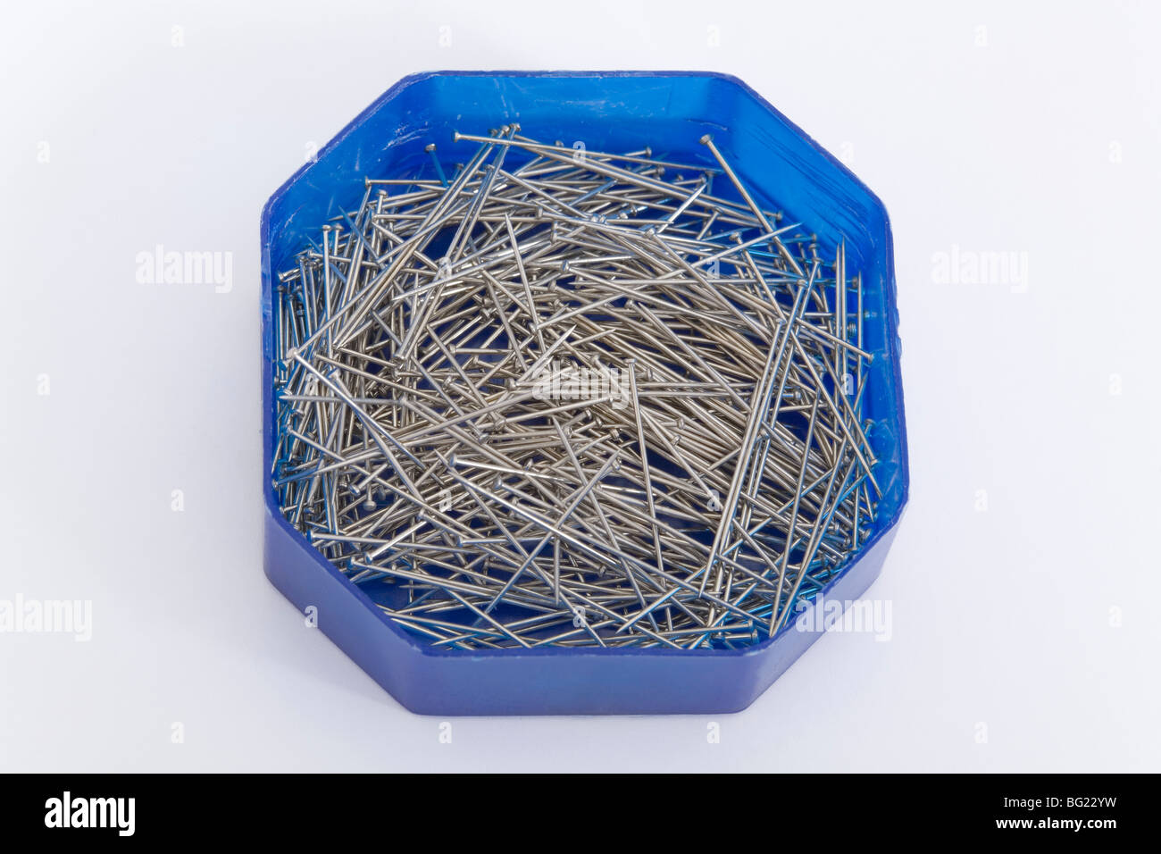 One octagonal blue plastic box container with metal needles on white background clothing sweing tailor item object domestic use Stock Photo