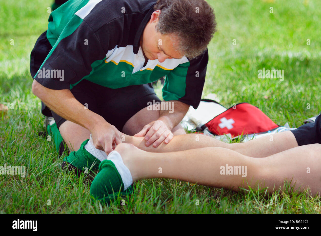 Man administering first aid to person's ankle Stock Photo - Alamy