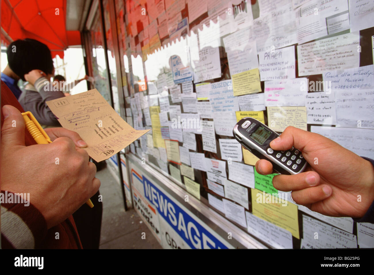 Polish migrant workers looking for work read job adverts in a Polish shop window in west London Stock Photo
