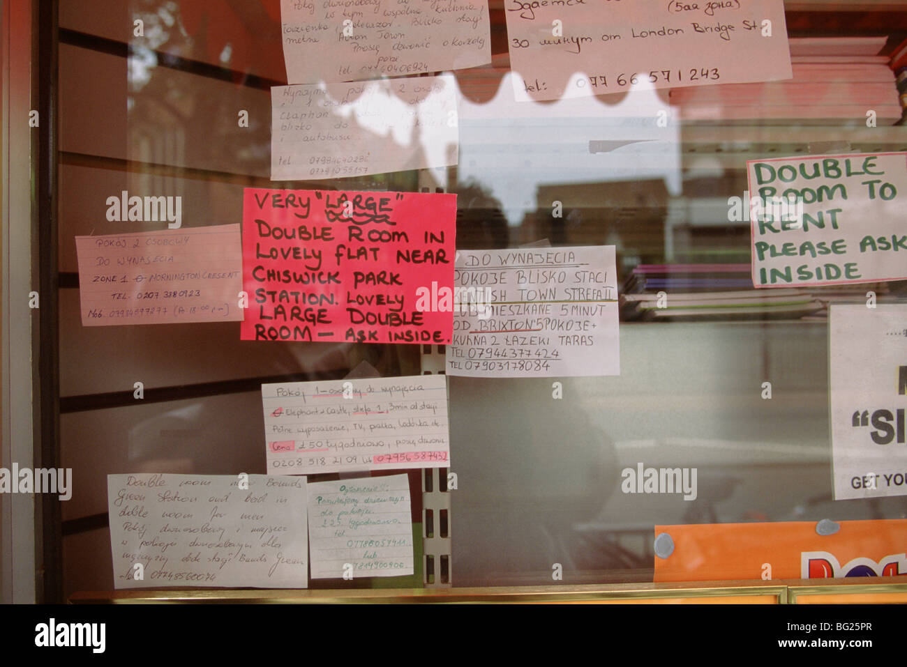 Polish migrant workers looking for work read job adverts in a Polish shop window in west London Stock Photo