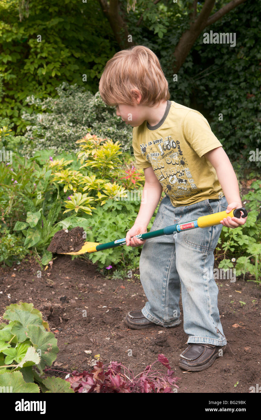three year old boy digging in the garden Stock Photo