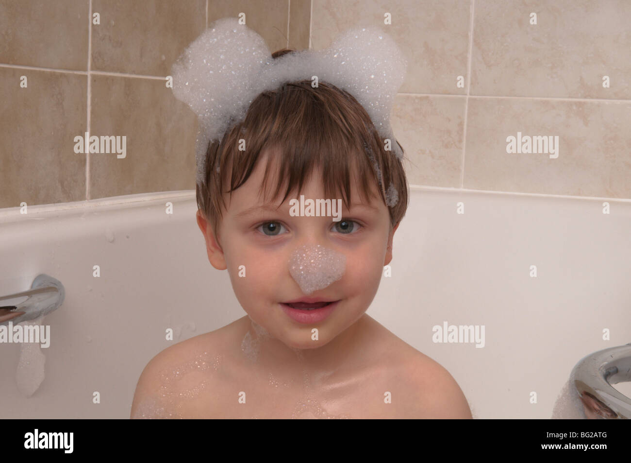 boy threeandonehalf years old playing in bubble bath with bubbles in