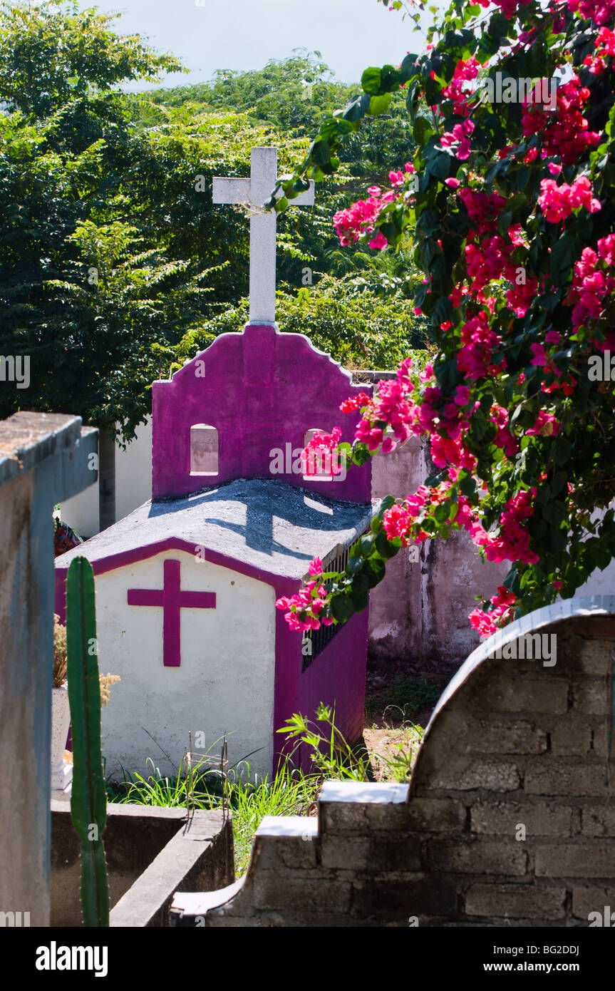 A brightly painted gravesite bordered by pink bougainvillea adds beauty to this rural cemetery in Nayarit, Mexico. Stock Photo