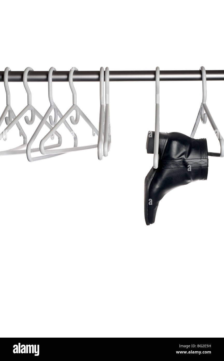 Black leather boot hanging from a hanger on a closet pole Stock Photo