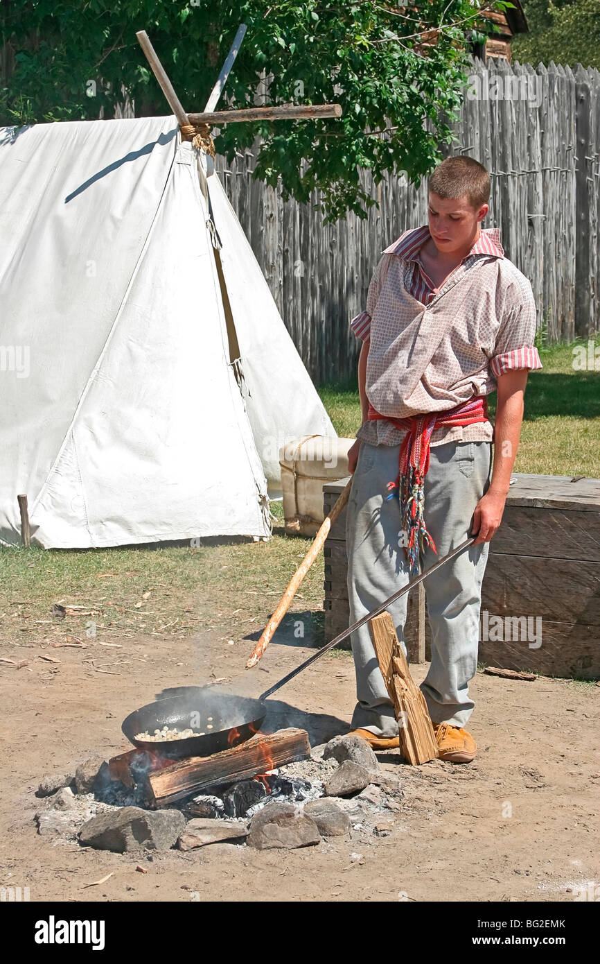 Voyageur (pioneer working man) cooks up typical meal of corn fried in bear grease at Fort William Historical Park, Thunder Bay Stock Photo