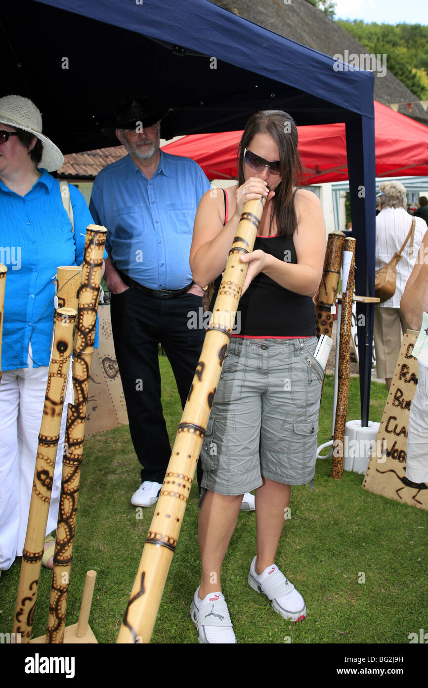 Young woman playing the Australian Aboriginal musical instrument called the Didgeridoo at a street fair and market Stock Photo