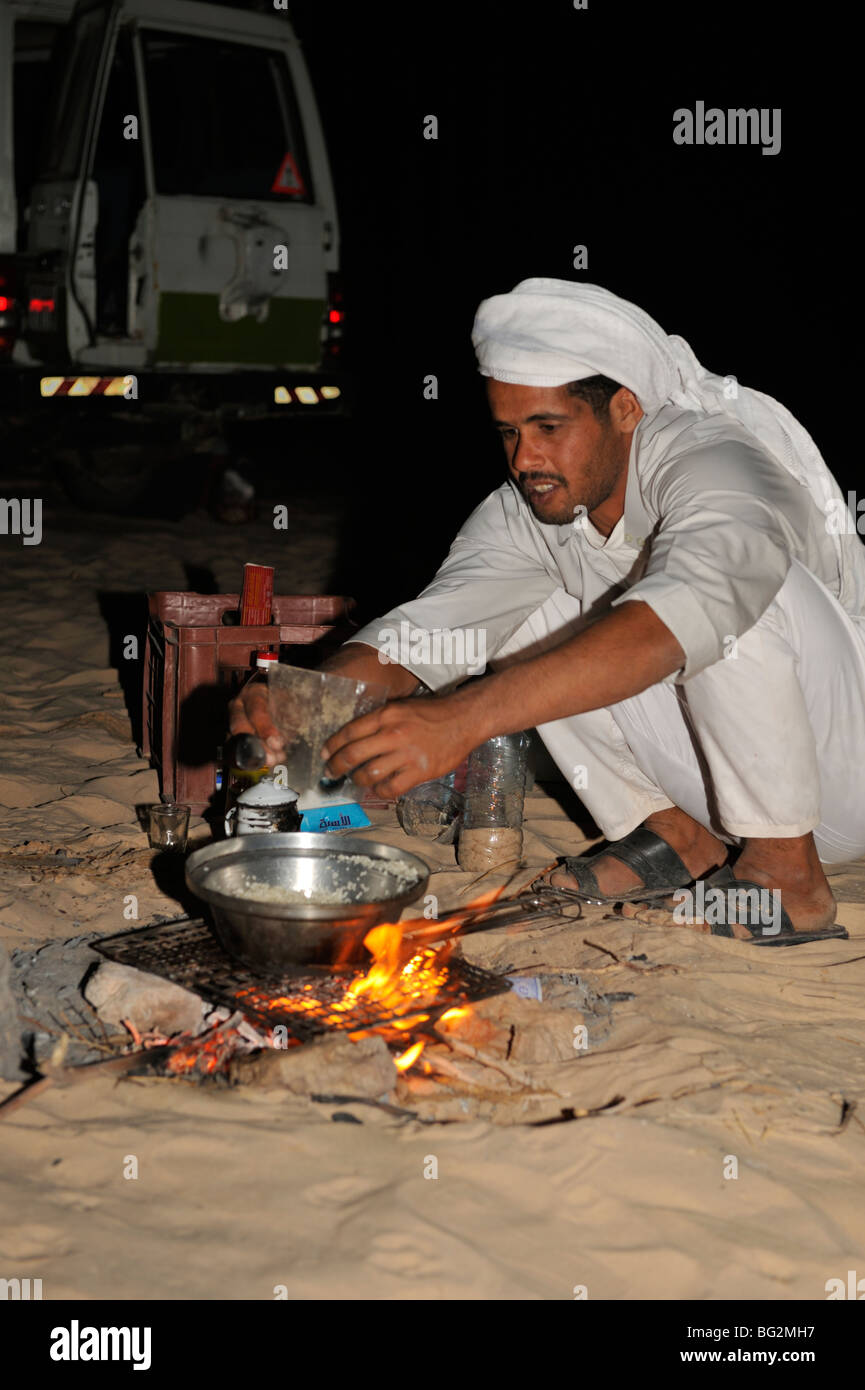 Bedouin men cooking meal in the desert over fire at night on desert