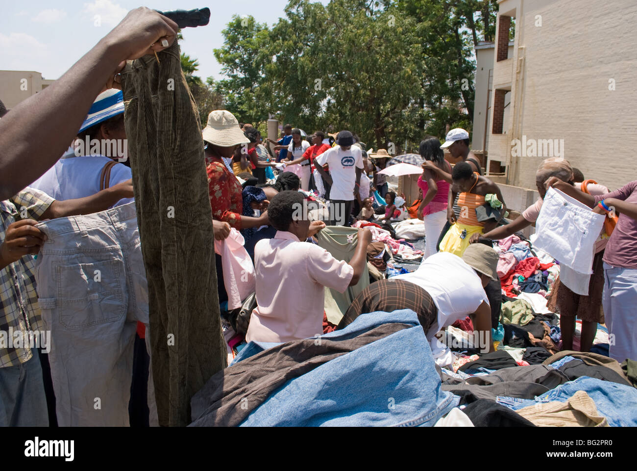 Bargain hunters rummage through second hand clothing at the 'Bend Over' Bazaar in Bulawayo, Zimbabwe. Stock Photo