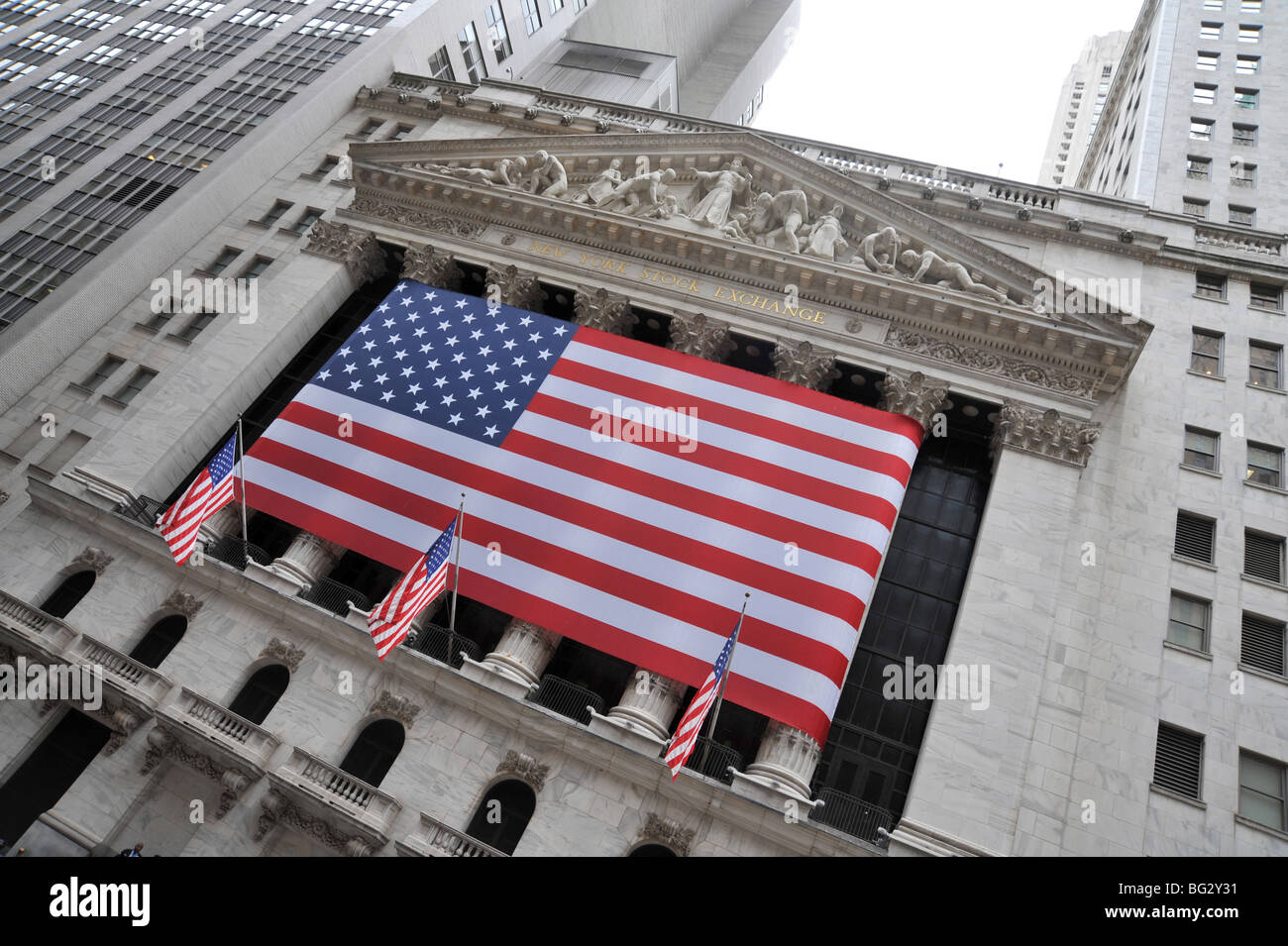 New York Stock Exchange on Wall St with huge Stars and Stripes flag across the front Stock Photo