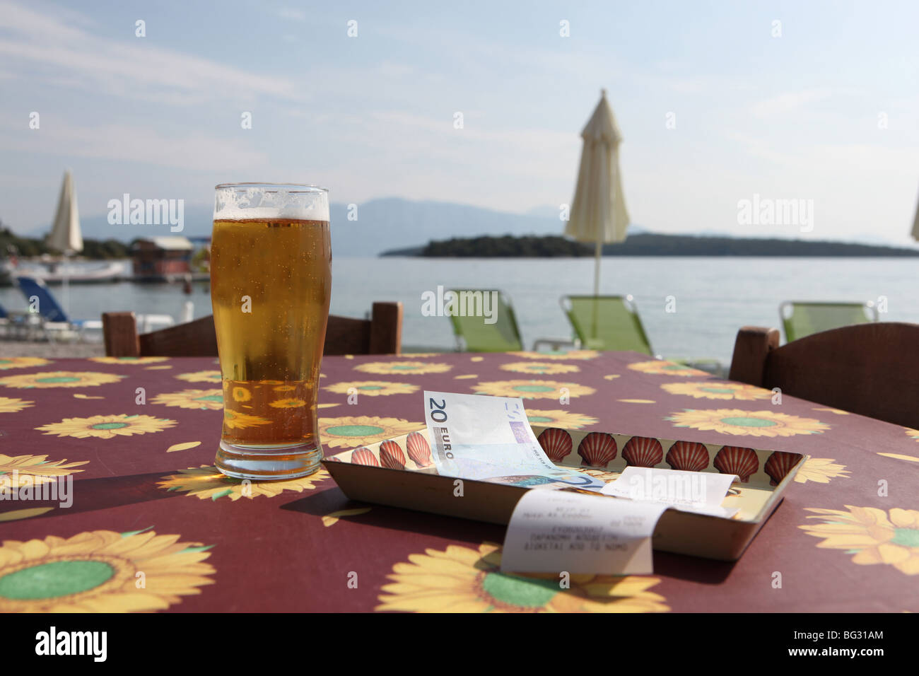 Restaurant on the beach, receipt on a tray with a bank note payment. Refreshing glass of beer. Stock Photo