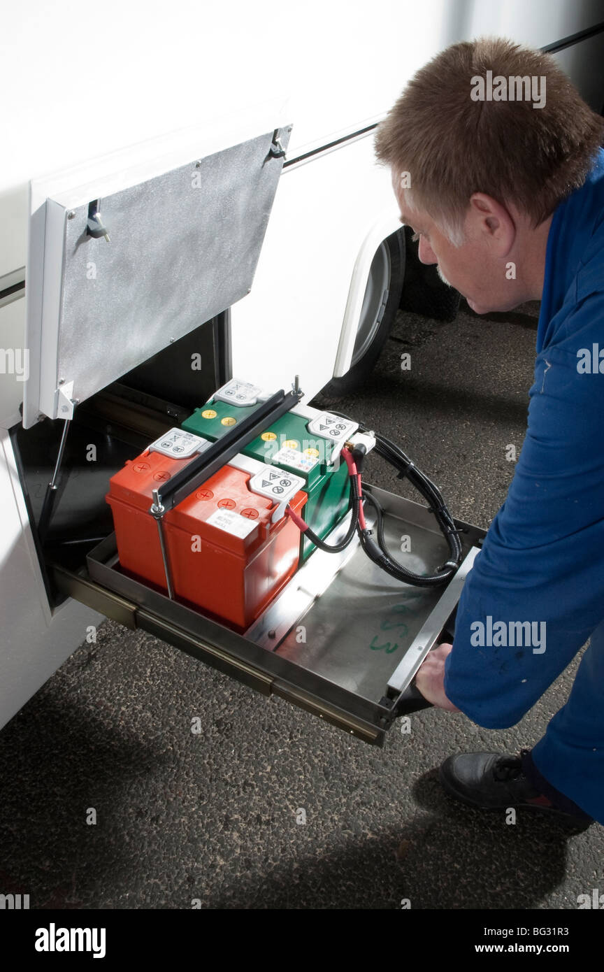 Maintenance engineer sliding vehicle batteries out of battery