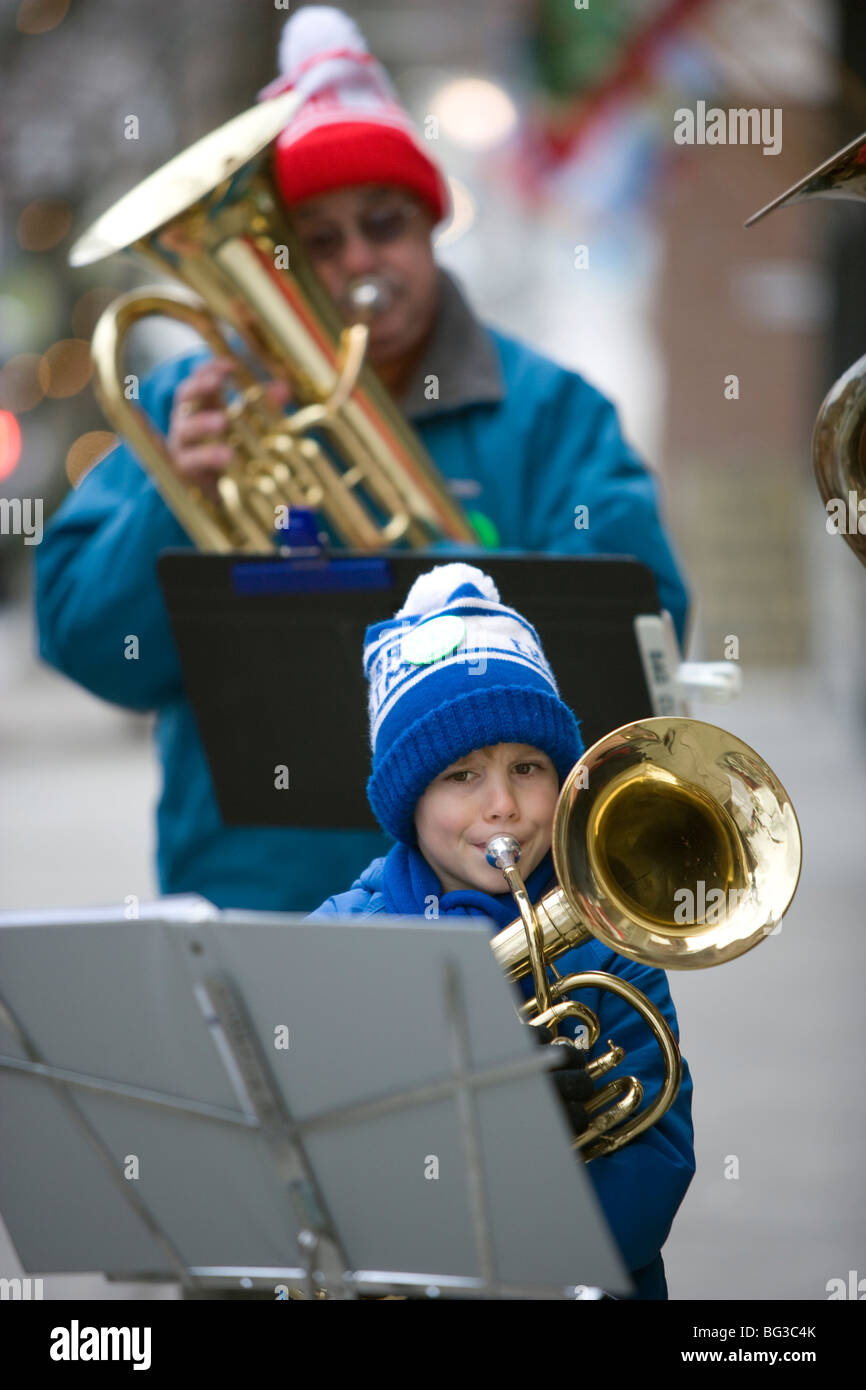 Small musician blows his horn as a group of local musicians the street for an impromptu Christmas concert Stock Photo