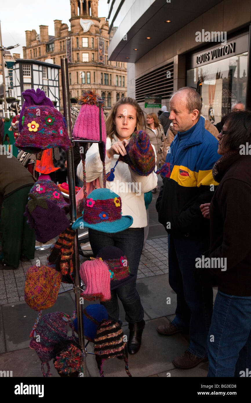 UK, England, Manchester, Christmas Market, shoppers looking at warm hats on festive clothing stall Stock Photo
