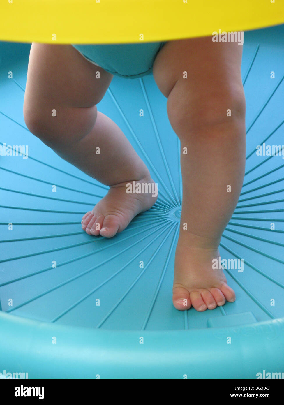 Legs and feet of an infant learning to walk in a blue environment Stock