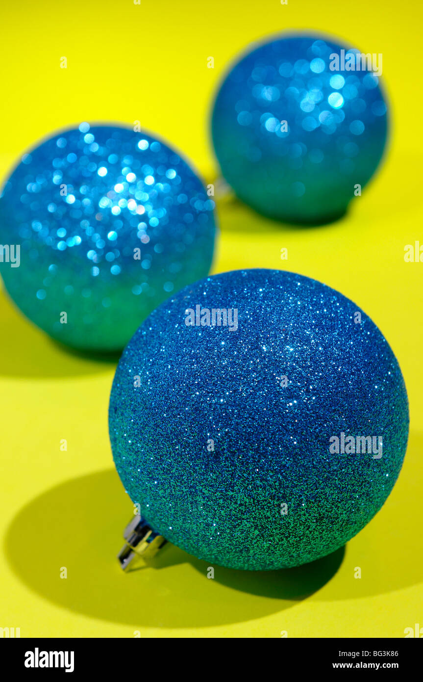 Sparkling blue globe Christmas decorations under spotlights on a yellow