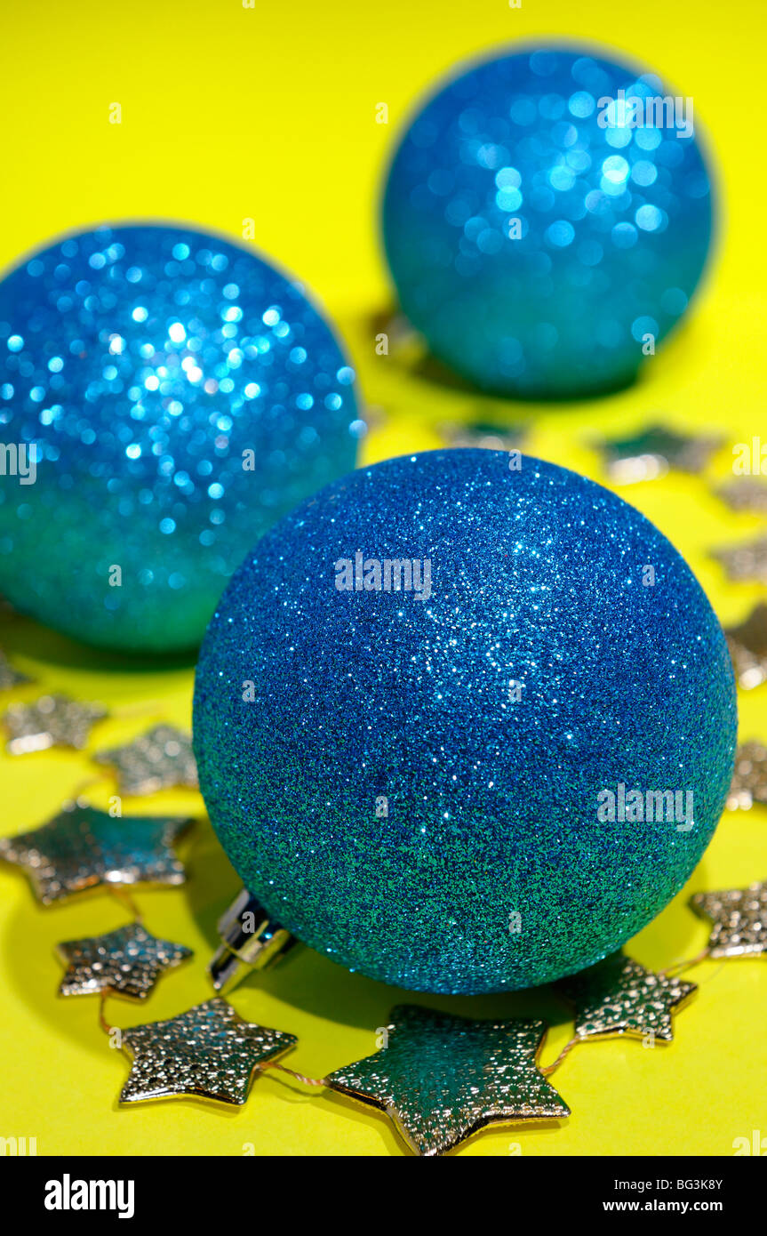 Sparkling blue globe Christmas decorations and gold stars on a yellow