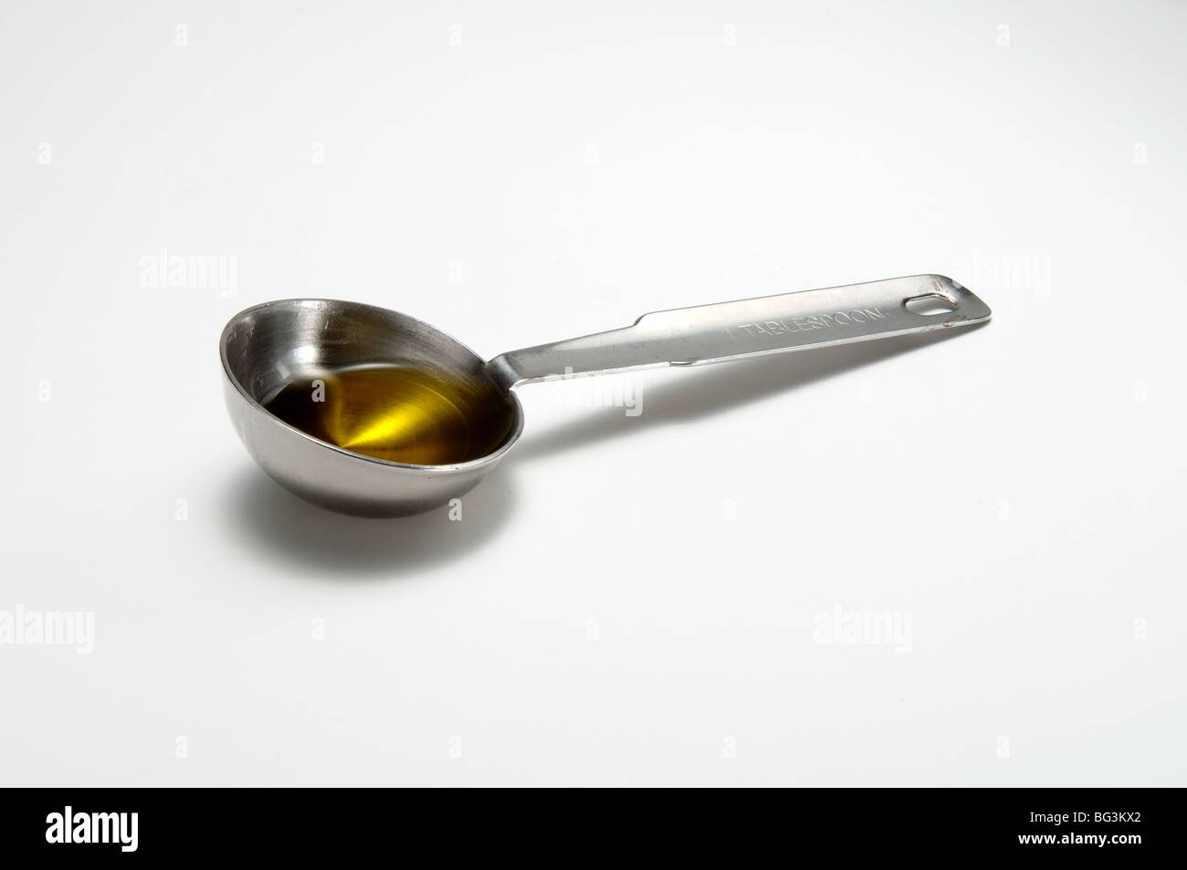 A metal measuring tablespoon and olive oil inside Stock Photo Alamy