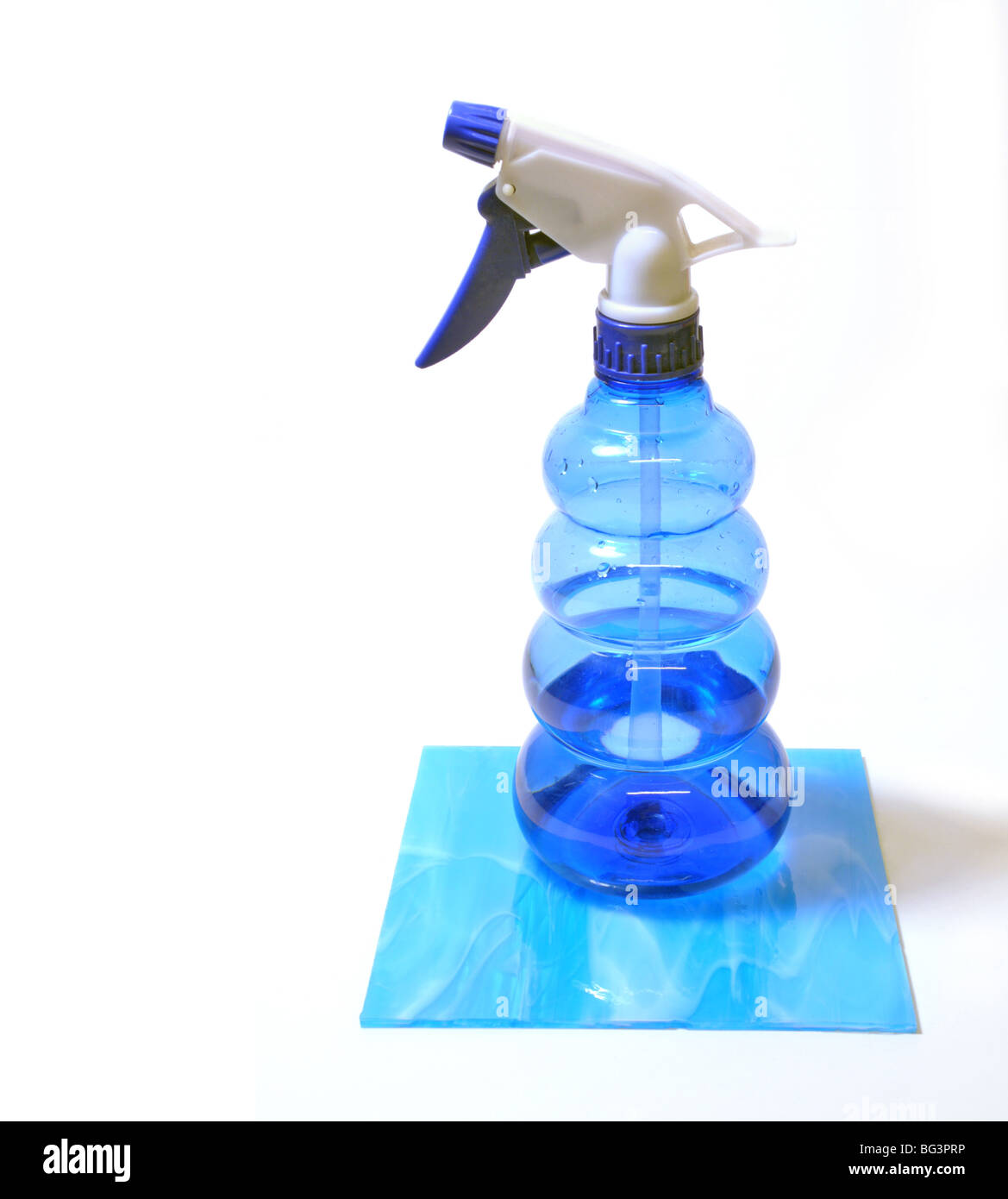 A cut out of a blue plastic spray bottle filled with water sitting on a blue tile. Stock Photo