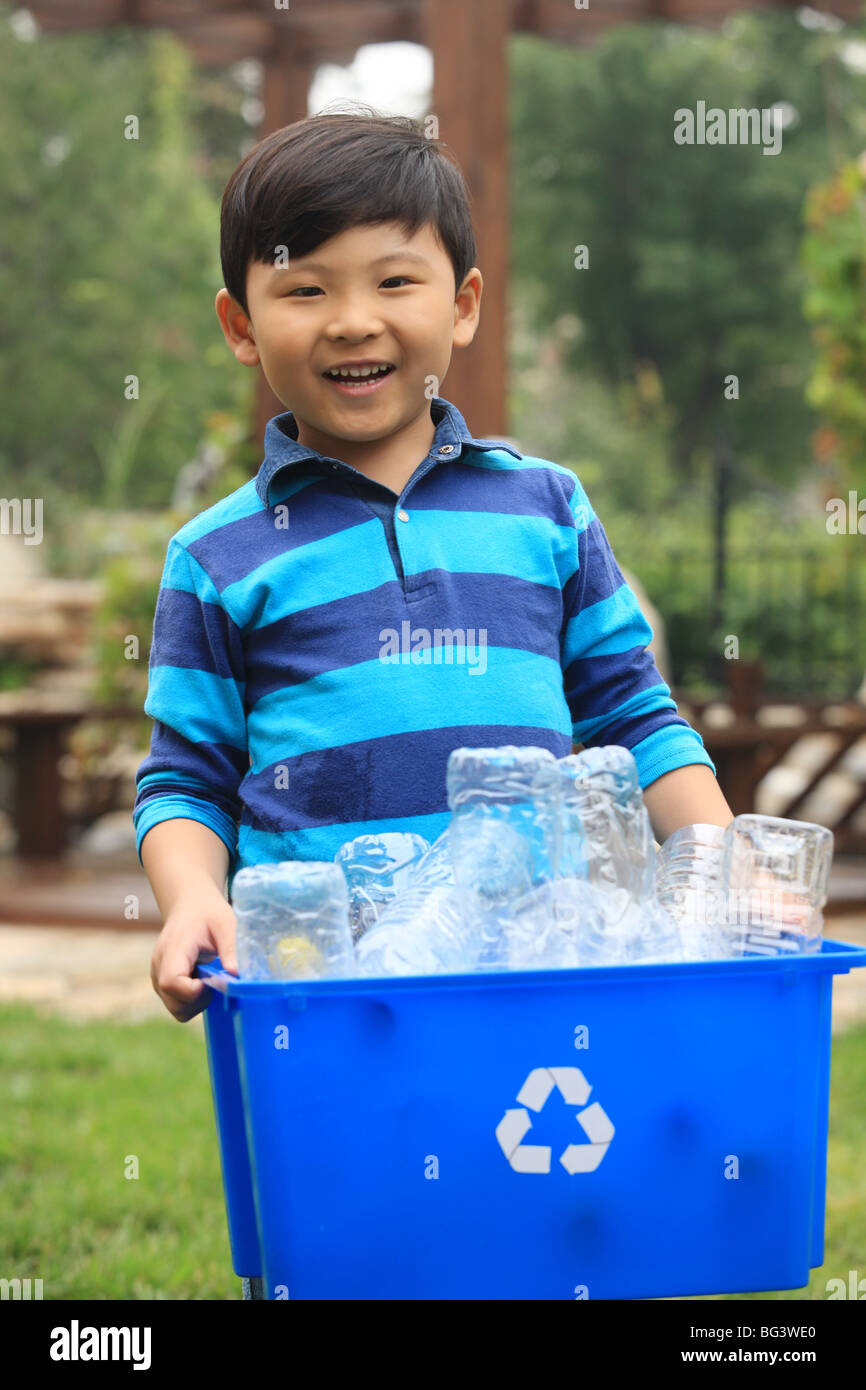 boy holding recycling container with empty plastic bottles inside Stock