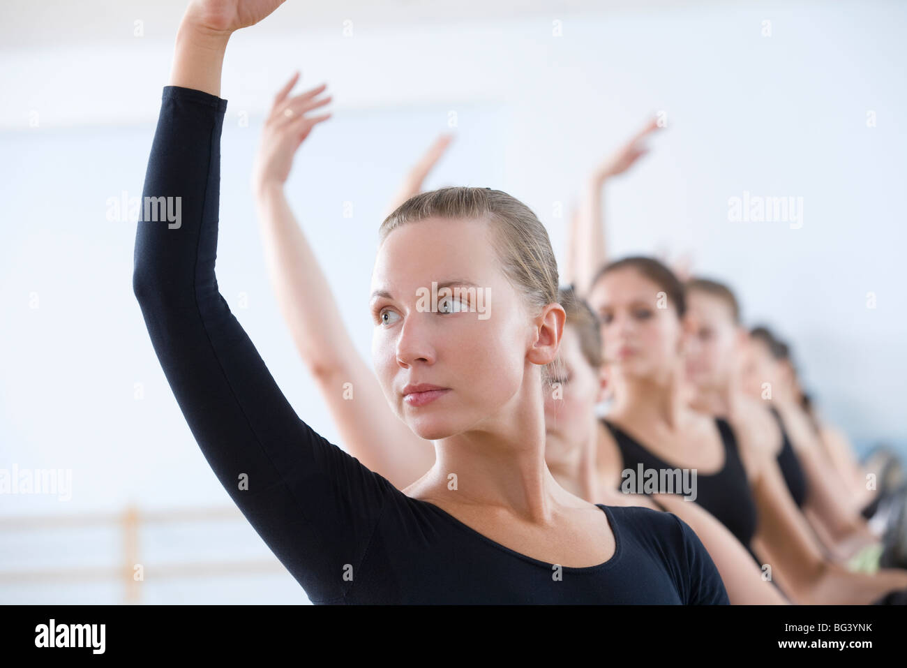 Young women with arms raised at the barre Stock Photo