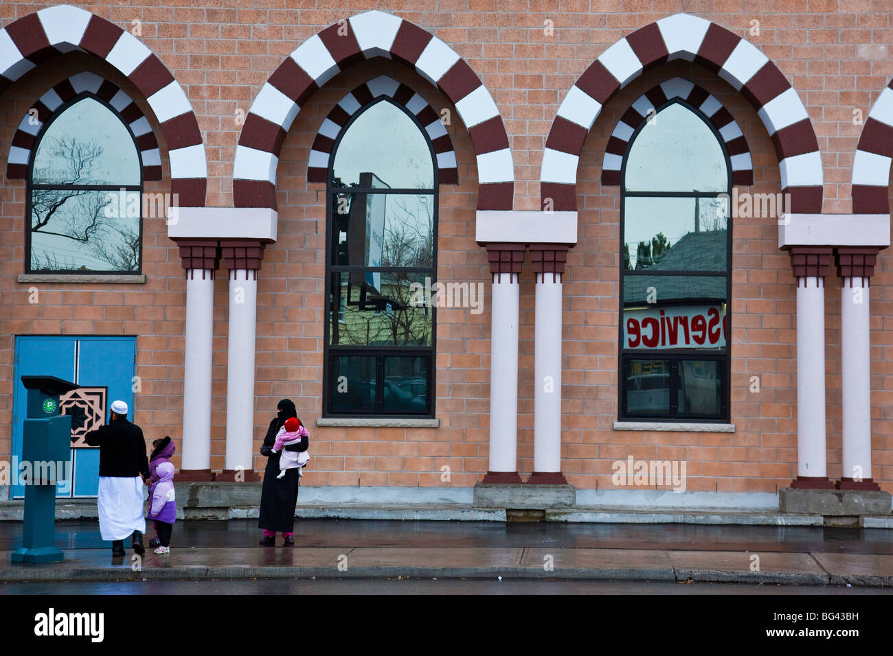 Muslim man paying a parking meter in front of Madina Masjid in Toronto Canada Stock Photo