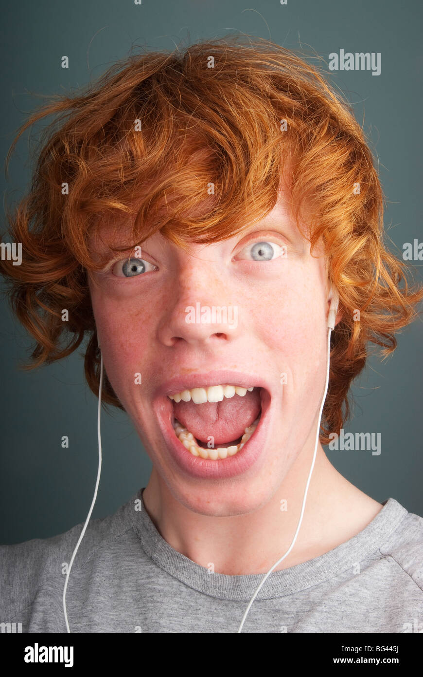 Ginger haired teenage boy listens to music Stock Photo