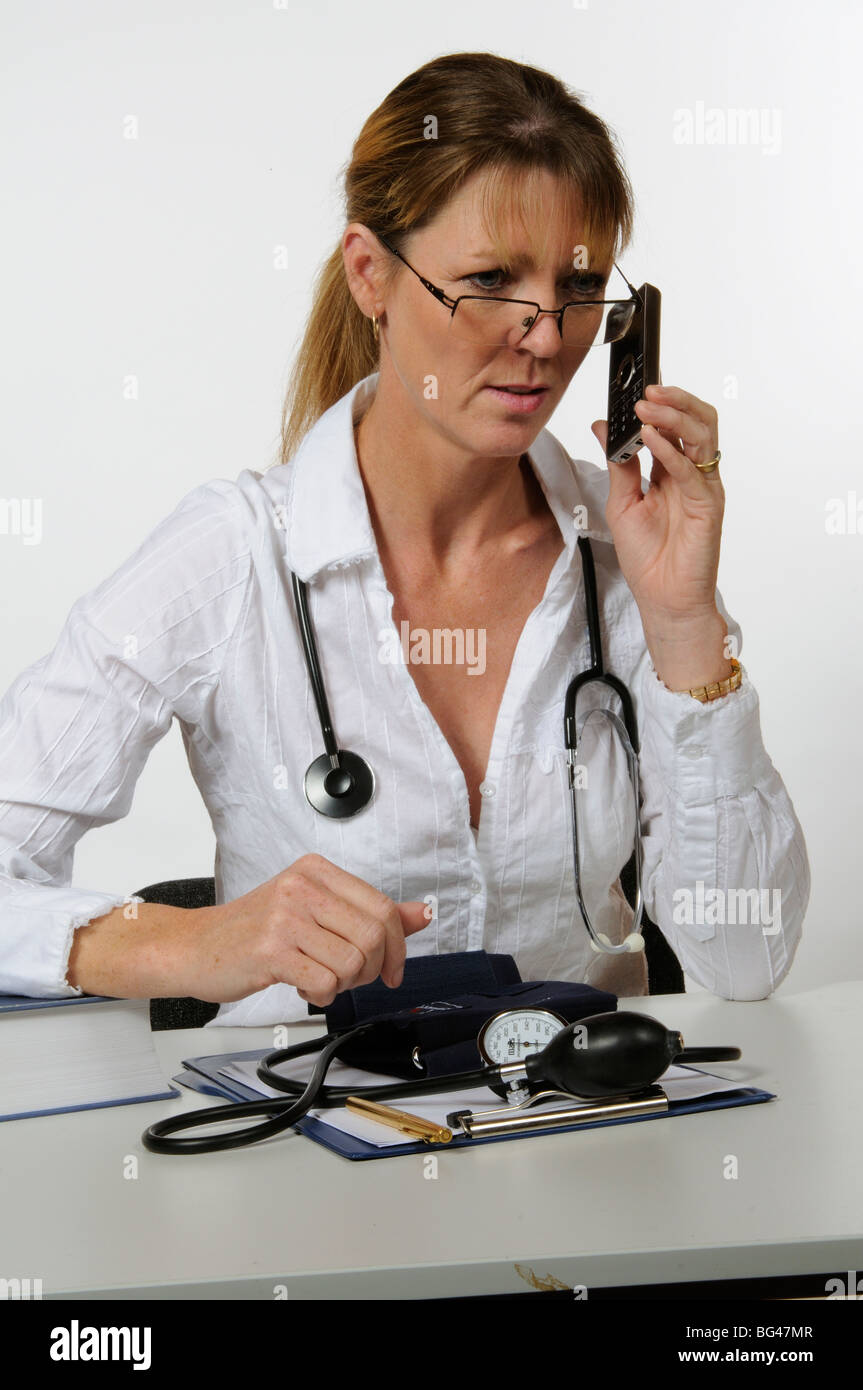 Female doctor taking or making a telephone call from her desk Stock Photo