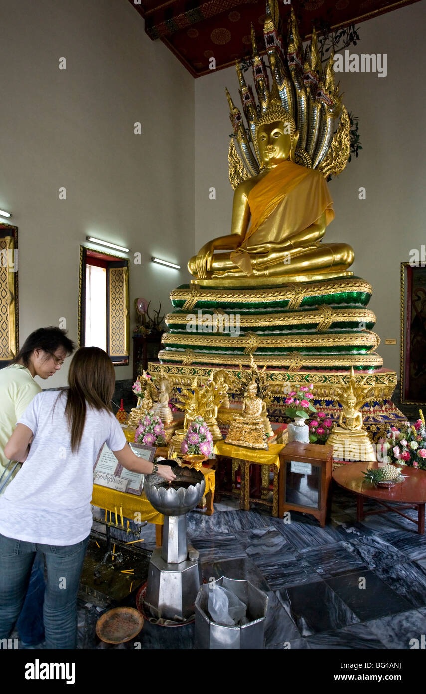 Thai couple making an offering to Buddha. Wat Pho. Bangkok. Thailand Stock Photo